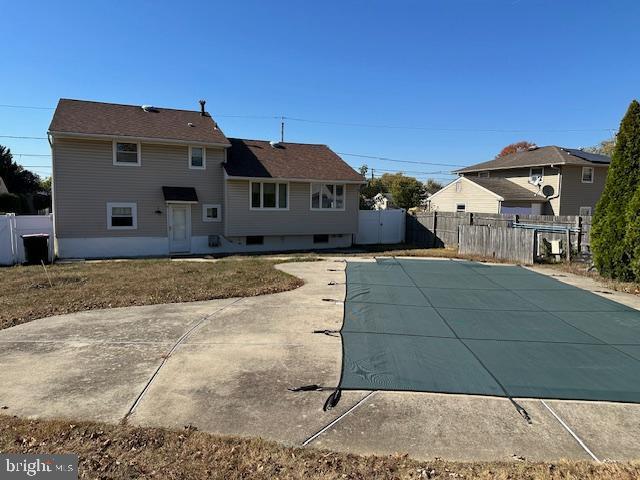 rear view of house featuring a covered pool and a patio area