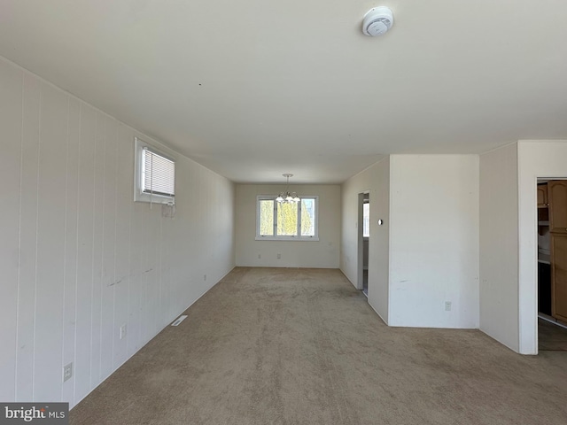 unfurnished room with light carpet and a notable chandelier