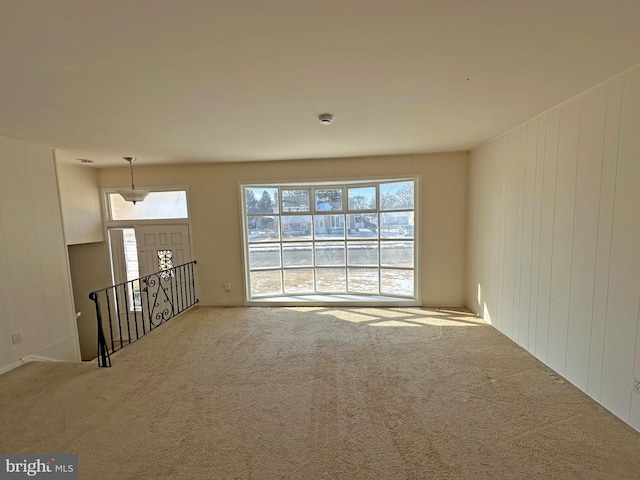 unfurnished room with light carpet and wooden walls