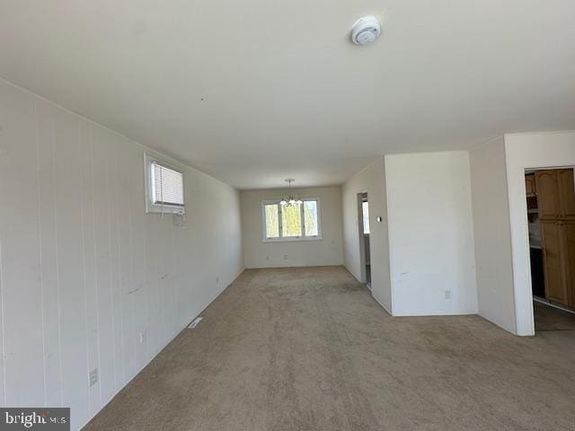 carpeted spare room featuring a chandelier