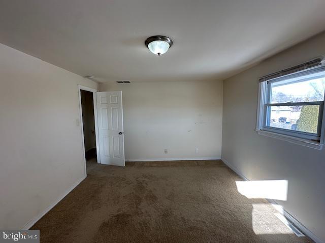 spare room featuring dark carpet