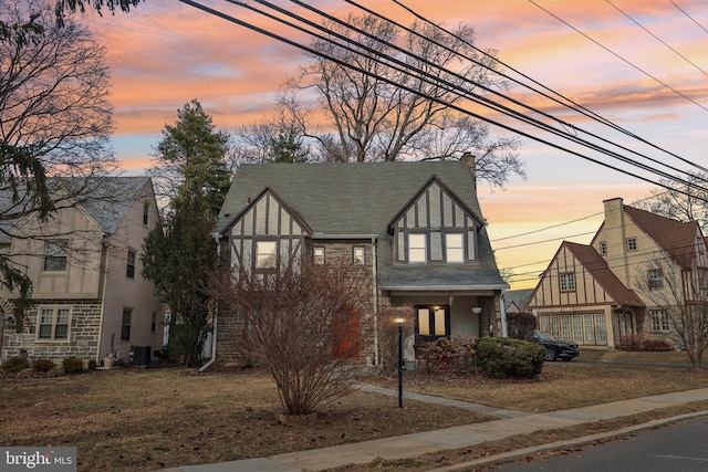 tudor-style house with a chimney, cooling unit, and stucco siding