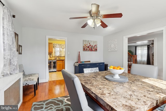 dining room with light wood-style floors, wine cooler, and a ceiling fan