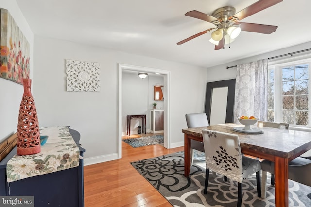 dining room with a ceiling fan, baseboards, and light wood finished floors