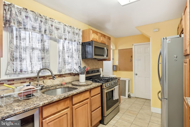 kitchen featuring beverage cooler, stainless steel appliances, a sink, decorative backsplash, and light stone countertops