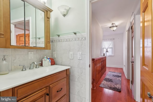 bathroom featuring wood finished floors, vanity, and tile walls