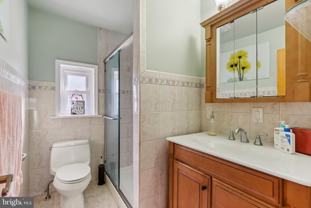 full bath featuring toilet, a stall shower, tile walls, and vanity