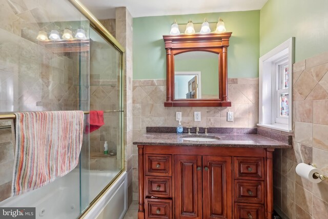 full bath featuring enclosed tub / shower combo, vanity, and tile walls