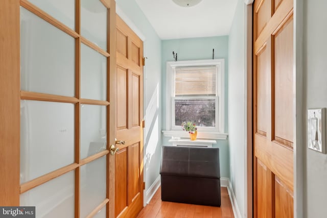 doorway with light wood-type flooring and baseboards