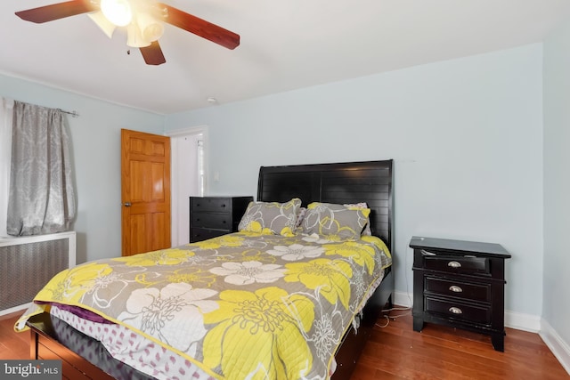 bedroom with a ceiling fan, radiator, baseboards, and wood finished floors