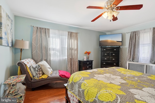 bedroom with a ceiling fan, radiator, and wood finished floors