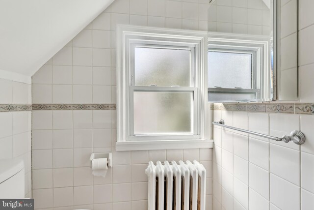 bathroom with radiator, toilet, tile walls, and lofted ceiling