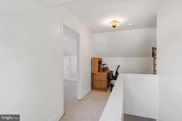 hall featuring light colored carpet, vaulted ceiling, and baseboards