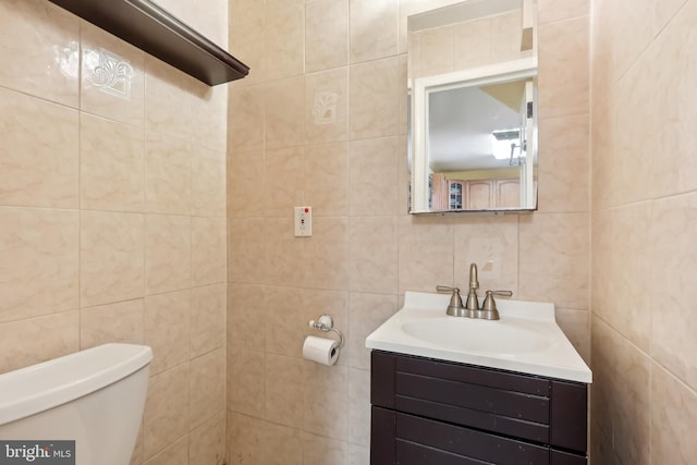 bathroom with vanity, toilet, and tile walls