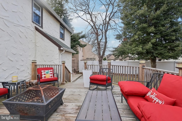 wooden deck featuring an outdoor living space with a fire pit and fence