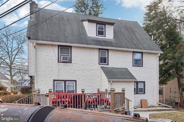 rear view of property with a wooden deck, a shingled roof, and stucco siding