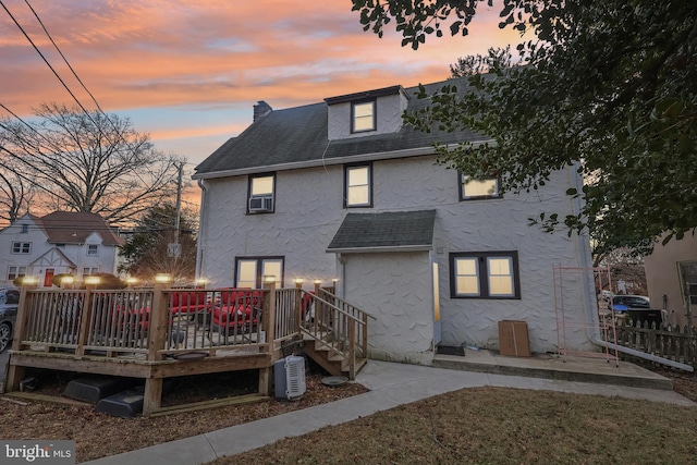 rear view of property featuring roof with shingles, a wooden deck, and stucco siding