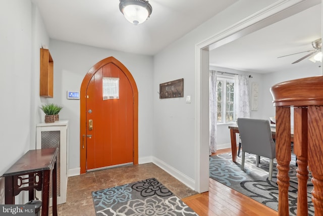 entryway featuring arched walkways, ceiling fan, baseboards, and wood finished floors