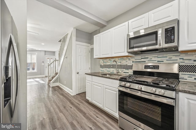 kitchen featuring white cabinetry, sink, dark stone counters, and appliances with stainless steel finishes