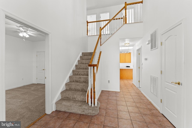 entryway featuring ceiling fan, a high ceiling, and light tile patterned flooring