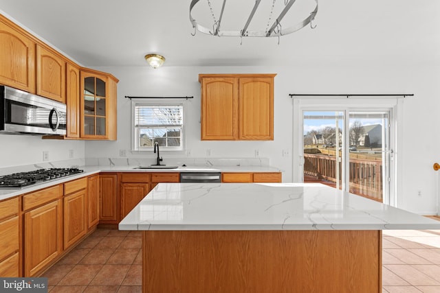 kitchen featuring sink, light tile patterned floors, a center island, and appliances with stainless steel finishes