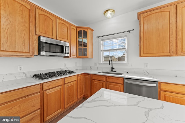 kitchen with light stone countertops, appliances with stainless steel finishes, and sink