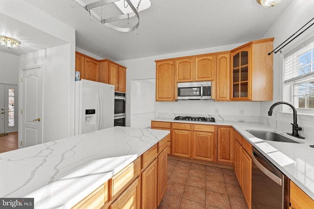 kitchen featuring sink, light tile patterned floors, stainless steel appliances, and light stone countertops