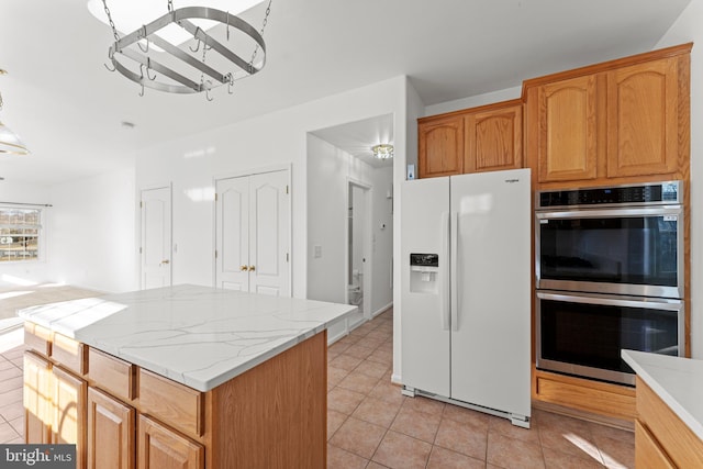 kitchen featuring light tile patterned flooring, stainless steel double oven, a center island, and white refrigerator with ice dispenser