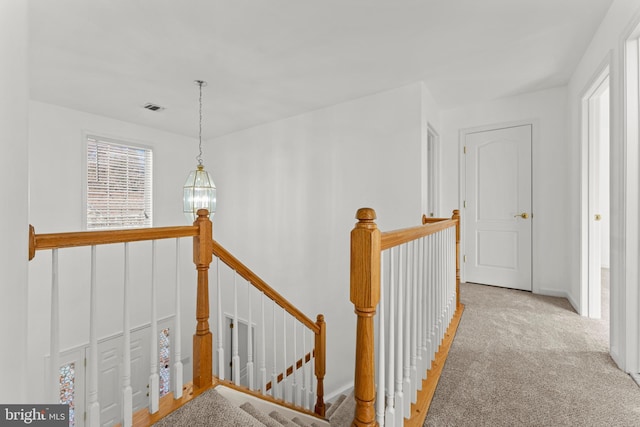 corridor featuring light colored carpet and a chandelier