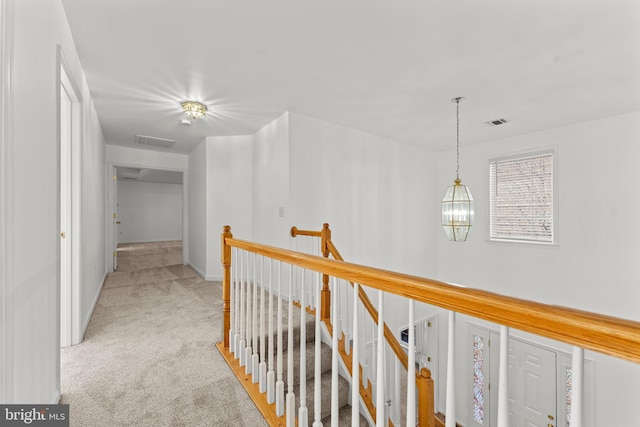 hall with light colored carpet and a chandelier