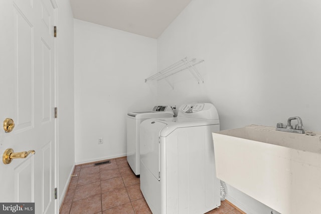 washroom featuring sink, washer and dryer, and light tile patterned floors