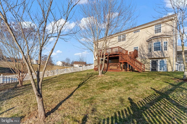 rear view of house featuring a wooden deck and a lawn