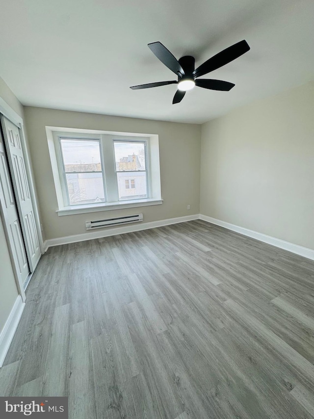 spare room featuring ceiling fan, a baseboard radiator, and light hardwood / wood-style flooring