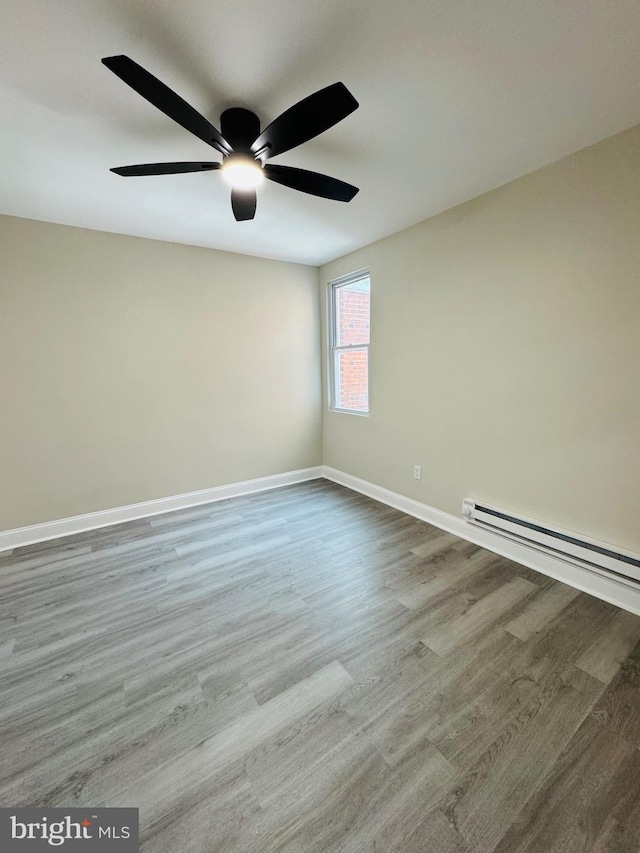 empty room with a baseboard heating unit, light hardwood / wood-style flooring, and ceiling fan