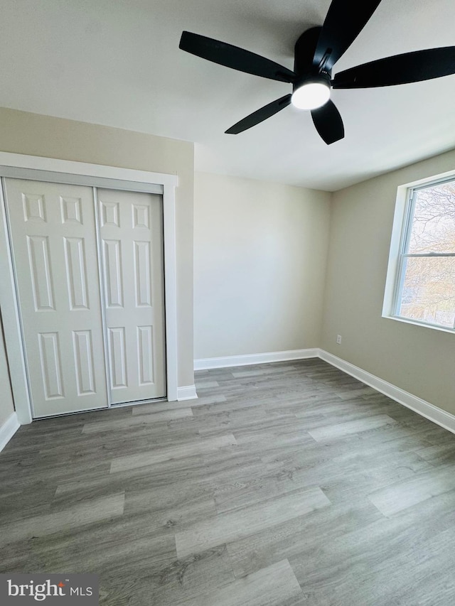 unfurnished bedroom with light hardwood / wood-style flooring, ceiling fan, and a closet