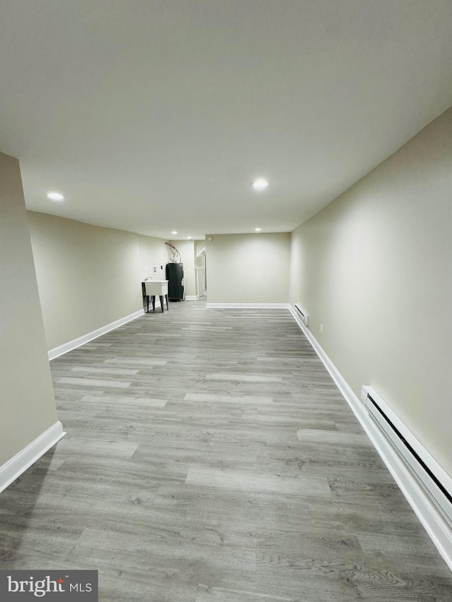 basement featuring light hardwood / wood-style flooring and a baseboard radiator