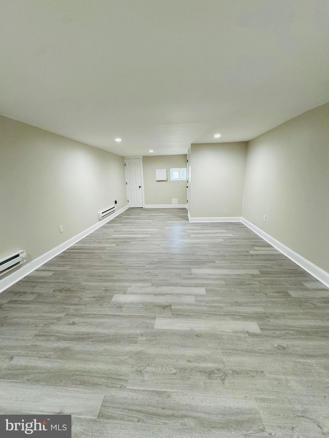 interior space with a baseboard heating unit and light hardwood / wood-style flooring