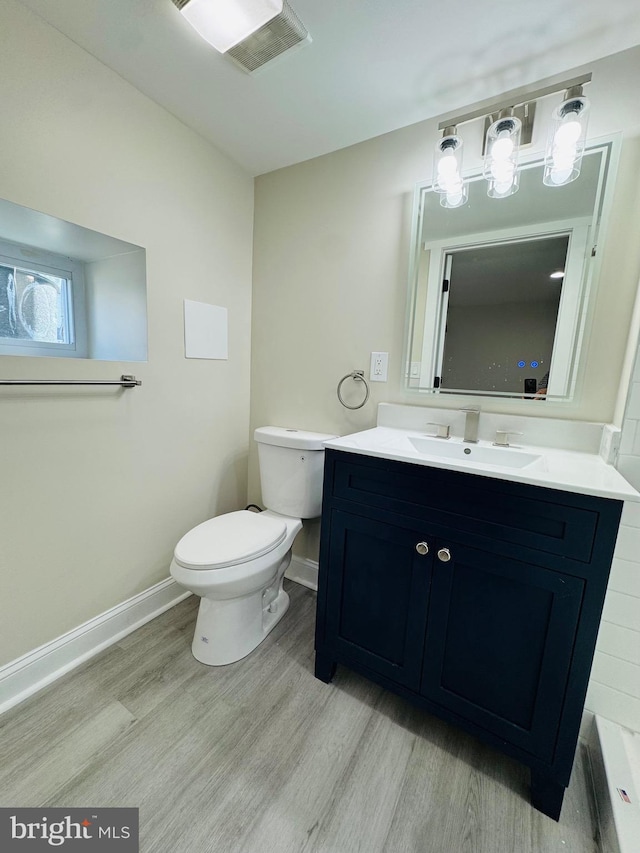 bathroom featuring vanity, wood-type flooring, and toilet