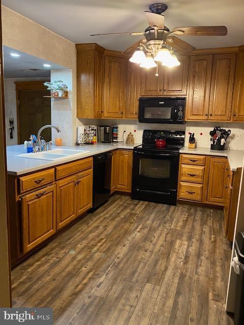 kitchen featuring sink, dark wood-type flooring, black appliances, and ceiling fan