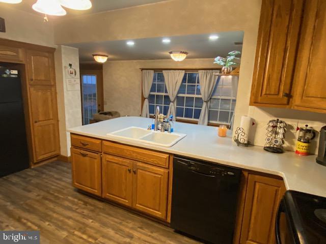 kitchen featuring sink, black appliances, dark hardwood / wood-style floors, and kitchen peninsula