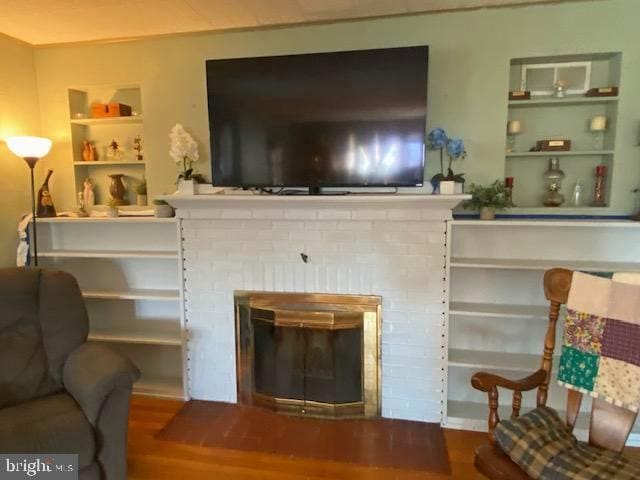 living area with hardwood / wood-style flooring, a fireplace, and built in features