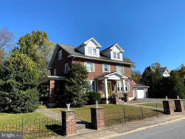 view of front of home with a garage, an outdoor structure, and a front yard