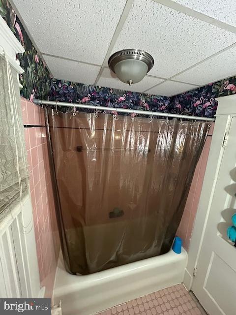 bathroom with a drop ceiling, tile patterned floors, and shower / tub combo with curtain