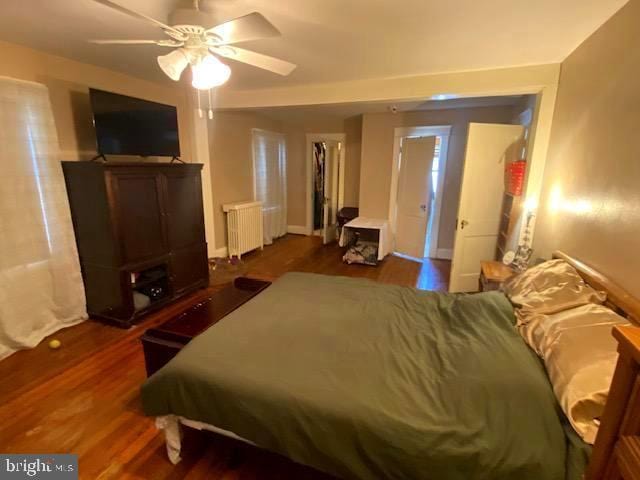 bedroom with radiator heating unit, dark hardwood / wood-style floors, and ceiling fan