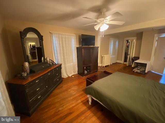 bedroom with hardwood / wood-style flooring, radiator heating unit, and ceiling fan