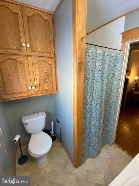 bathroom with a shower with shower curtain and toilet