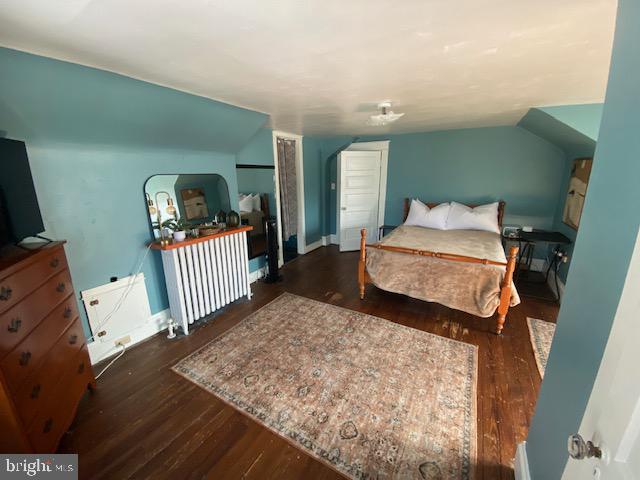 bedroom featuring vaulted ceiling, radiator, and dark hardwood / wood-style flooring