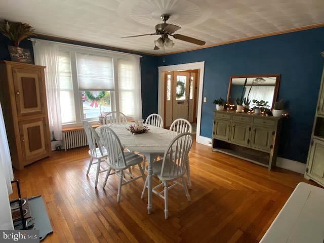 dining room featuring ornamental molding, radiator heating unit, ceiling fan, and light hardwood / wood-style flooring