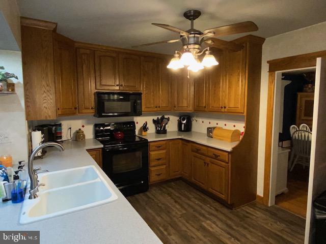 kitchen with dark wood-type flooring, ceiling fan, sink, and black appliances