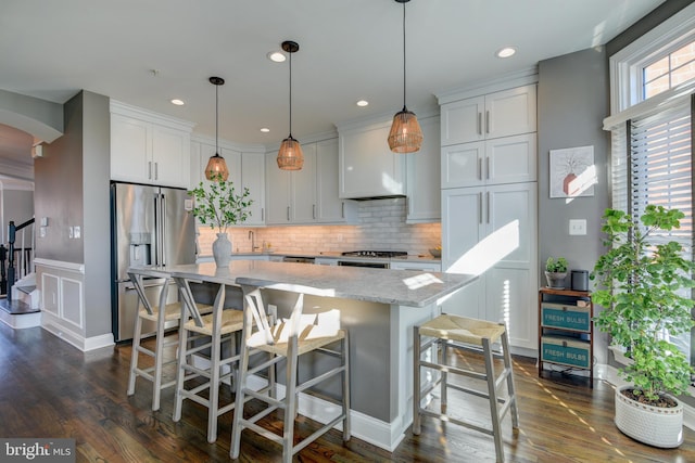 kitchen with white cabinetry, decorative light fixtures, high end fridge, and light stone counters